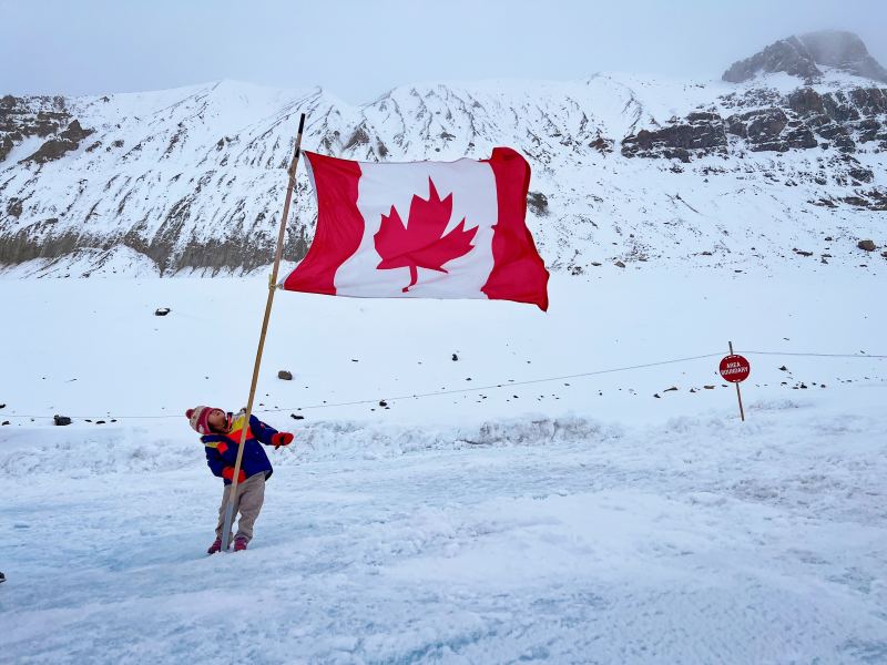A child holding a large Canadian flag on the Columbia Icefield