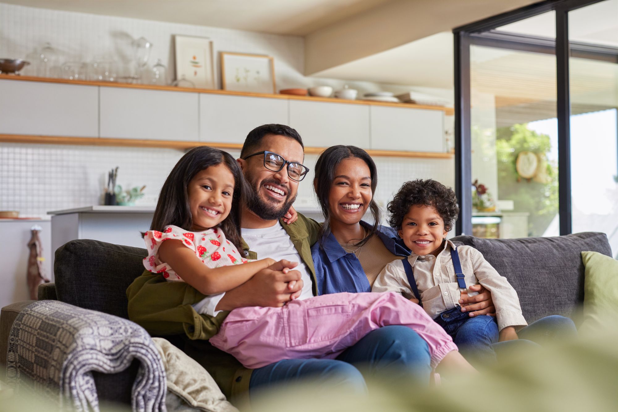 An Indian family laughing together on a sofa at home