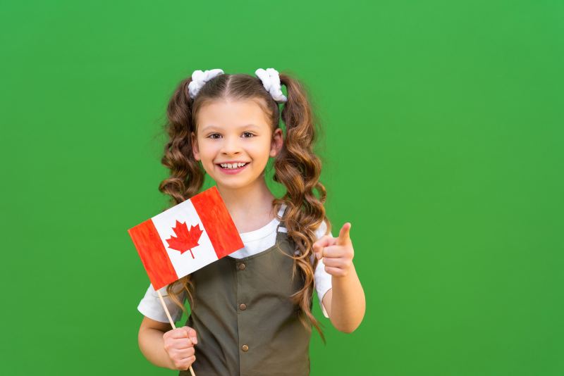 A schoolgirl holding the Canadian flag and pointing ahead