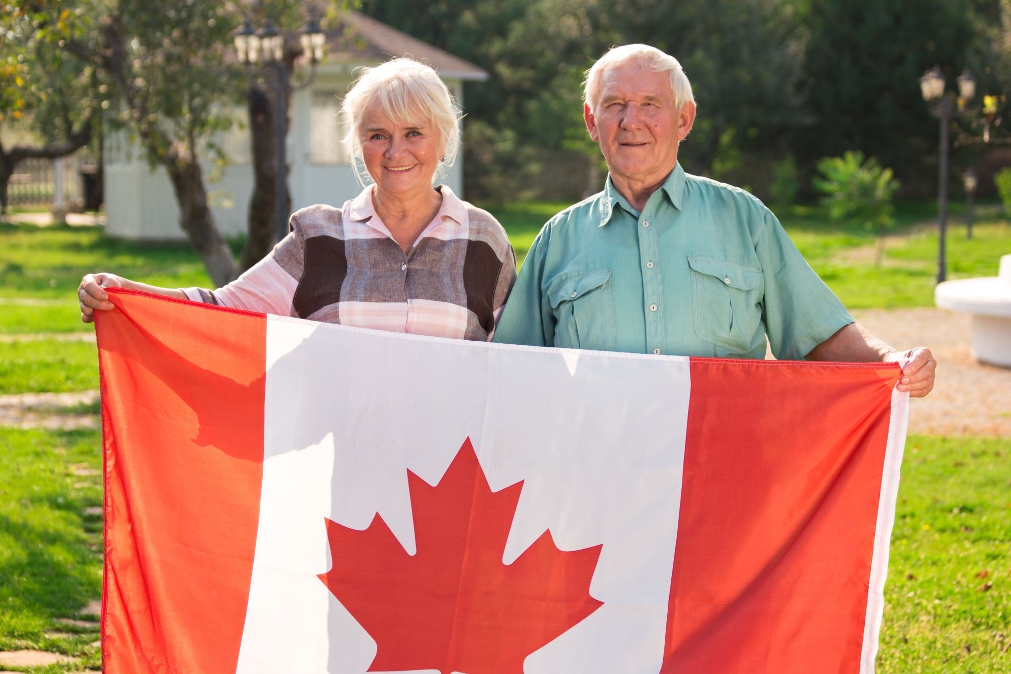 A senior couple holding the Canadian flag outdoors